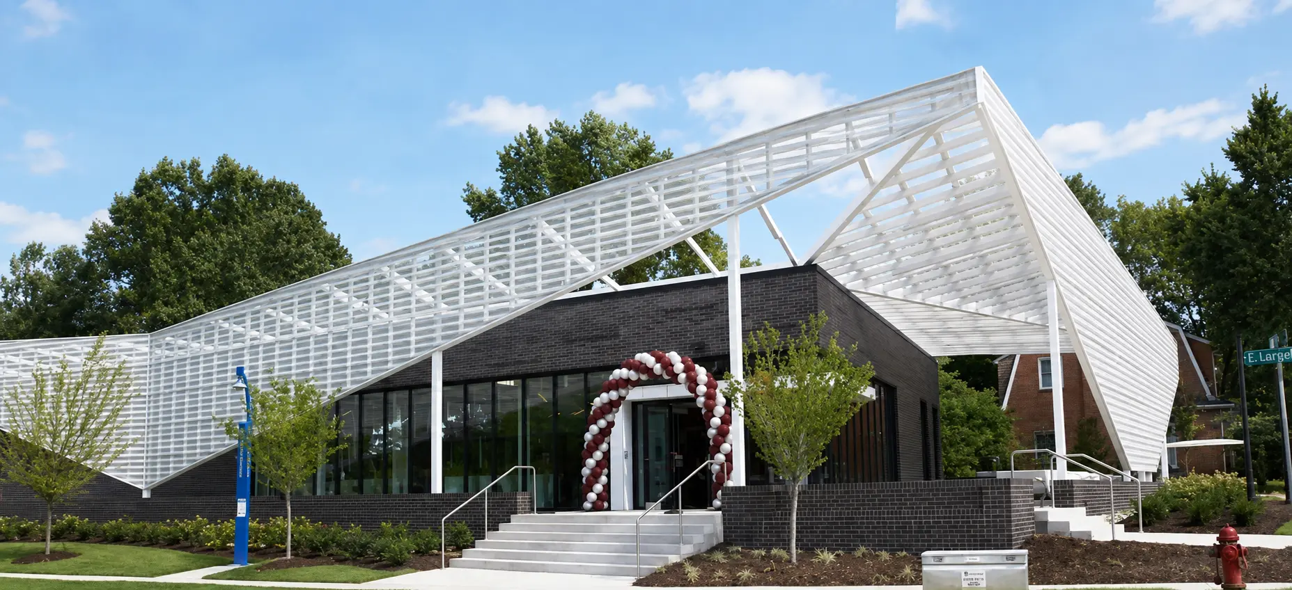 Modern academic building with a white sculptural canopy and a maroon and white balloon arch at the entrance on the NCCU campus